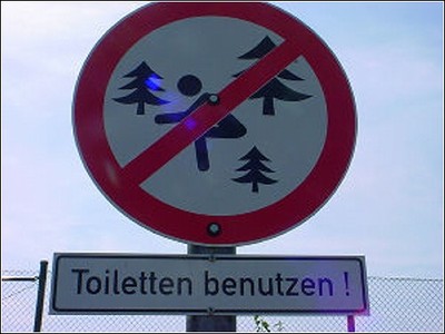 По-немецки:
"Пользуйтесь туалетом!"
И ниже (просто не видно): 
"В ЛЕСУ ПАРТИЗАНЫ!"
